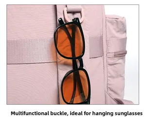Close-up of D-ring buckle on pink backpack strap holding sunglasses for outdoor hiking