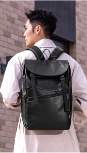 Detail of black faux leather backpack with flap closure and adjustable straps on model