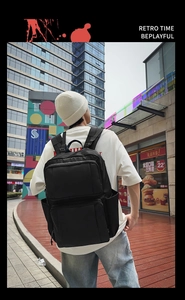 Street view of a black multi-pocket business laptop backpack on a male model's back