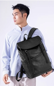 Detail view of the black PU leather business backpack with buckle closure on a male model