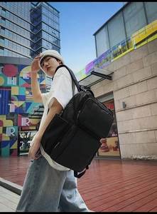 Close-up of black leather business backpack showing functional zipper pockets and durable fabric