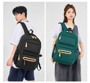 Detail of durable nylon backpack showing layered zipper pockets and brown leather pullers