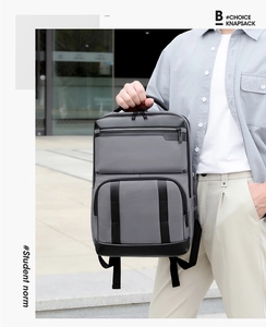 Close-up of a modern grey and black commuter backpack with layered zipper compartments