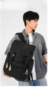 Detail of black nylon backpack featuring flap closure with dual buckles and multiple pockets