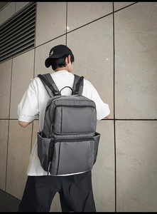 Detail view of dark grey business laptop backpack with multiple pockets on male model