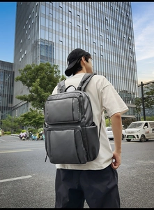 Deep grey business backpack with multi-pocket design shown in modern city street view