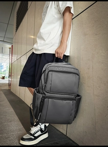 Side view of dark grey business backpack showing multi-zipper compartments and fabric texture