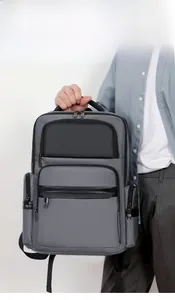 Grey large-capacity business backpack with black leather accents held by a male model