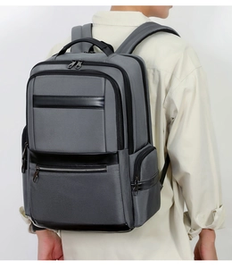 Men's grey Oxford cloth backpack with black leather trim shown in side view on model