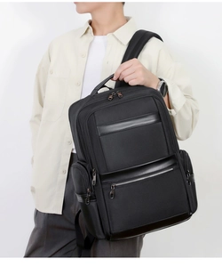 Man wearing a black waterproof Oxford commuter backpack with leather accents and multiple pockets