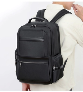 Side view of a black oxford commuter backpack with multiple zipper pockets on a male model