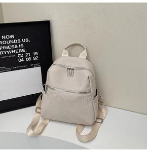 Détail d'un sac à dos crème avec surface texturée et fermetures éclair argentées