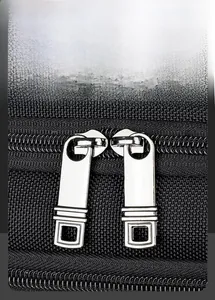 Close-up of dual smooth silver metal zippers on high-density black twill fabric backpack