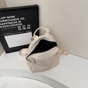 Détail du sac à dos tissé crème montrant la doublure noire et le compartiment