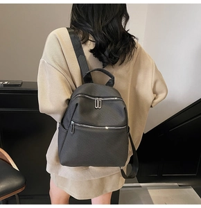 Détail d'un grand sac à dos gris foncé à texture géométrique porté par un mannequin