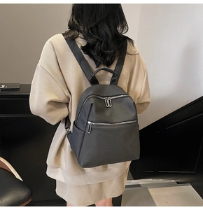 Close-up of black textured backpack featuring bold silver zippers and side pocket detail