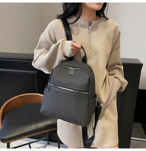 Fashionable dark gray leather backpack with silver zippers worn by a model in a studio