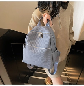 Detailed view of light blue fashion backpack with silver zippers on a model in modern interior