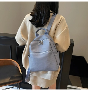 Detail view of the light blue textured backpack with dual front zippers and side pockets
