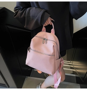 Vue détaillée du sac à dos rose à texture tressée avec doubles zips et poignée haute