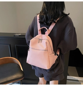 Detailed view of a pink fashionable backpack with textured finish and silver zippers