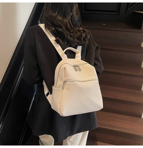 Détail du sac à dos crème avec texture diagonale porté par un mannequin élégant