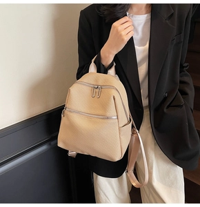 Gros plan d'un sac à dos tissé beige avec poches zippées sur un mannequin au style chic