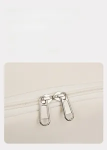 Close-up of smooth silver double metal zippers on beige durable fabric backpack