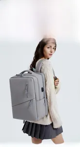 Gray waterproof laptop backpack with side USB port shown on model for daily commuting