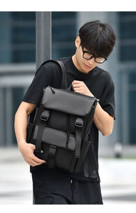 Outdoor shot of a black minimalist waterproof backpack with buckles on a male model