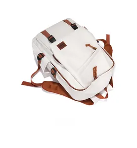 Detailaufnahme des weißen Rucksacks mit braunen Gurtbändern und Reißverschlusstaschen
