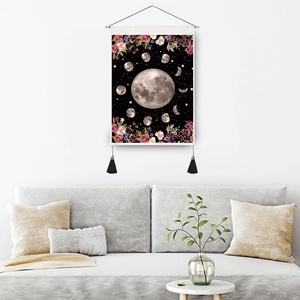 Bohemian moon phase wall tapestry with black tassels and wood scroll on a white wall