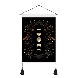 Detail of bohemian moon phase tapestry with vintage botanical prints and black tassels