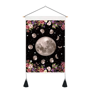 Detail of bohemian moon phase tapestry with floral patterns and black cotton tassels
