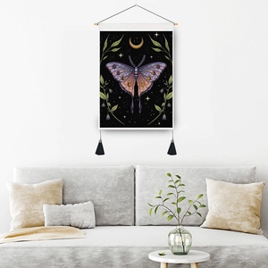 Nordic butterfly tapestry with moon phases and tassels hanging above a minimalist sofa