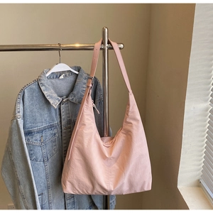 Pink waterproof nylon hobo bag hanging next to a denim jacket for a casual lifestyle look