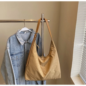 Detail of khaki large capacity hobo bag with adjustable strap hung on a stainless hanger