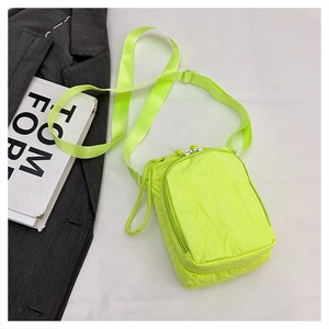 Detail of neon green nylon crossbody bag showing smooth zippers and adjustable strap