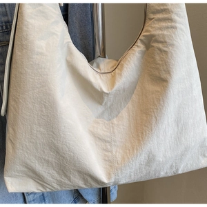 Detail shot of cream-white nylon tote bag showing textured fabric and crescent shape