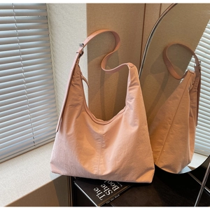 Detail of adjustable metal buckle and textured pink nylon strap on large hobo bag
