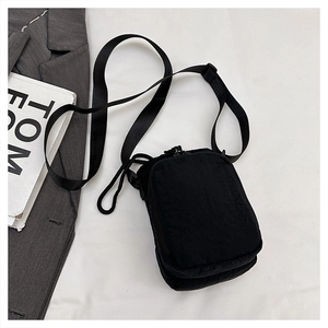 Detail of a black nylon crossbody phone bag with dual zippers and a wide shoulder strap