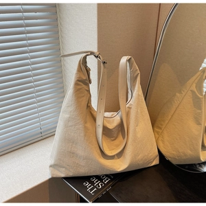Detail of a beige textured nylon tote bag featuring an adjustable strap and spacious design