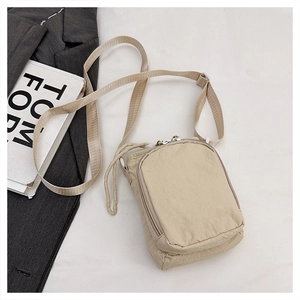 Detail of a beige nylon crossbody sports bag with zipper pocket and adjustable strap