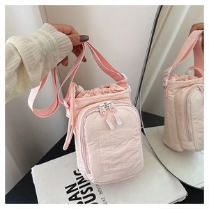 Detailed view of pink nylon crossbody bag with drawstring closure and white zippers