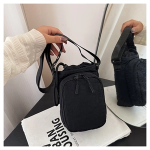 Detail of black nylon crossbody bag featuring drawstring closure and adjustable strap