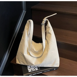 Close-up of beige hobo bag with wrinkled texture and adjustable silver buckle on wood