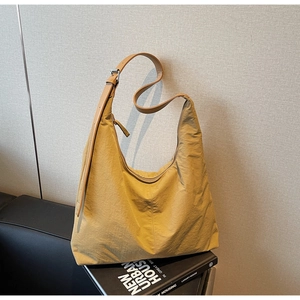 Detail of yellow nylon tote bag with brown leather strap and silver metal buckle