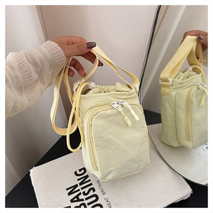 Close-up of a nylon crossbody bag with drawstring closure and dual-zippered front pocket