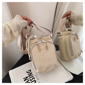 Detail of beige nylon crossbody bag showing drawstring closure and mirror reflection view