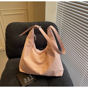 Detail of pink nylon tote bag showing crinkled texture on a velvet chair